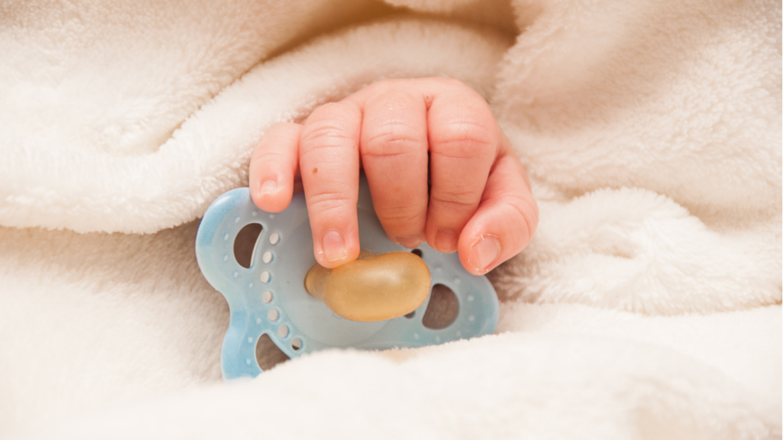 Baby holding a dummy